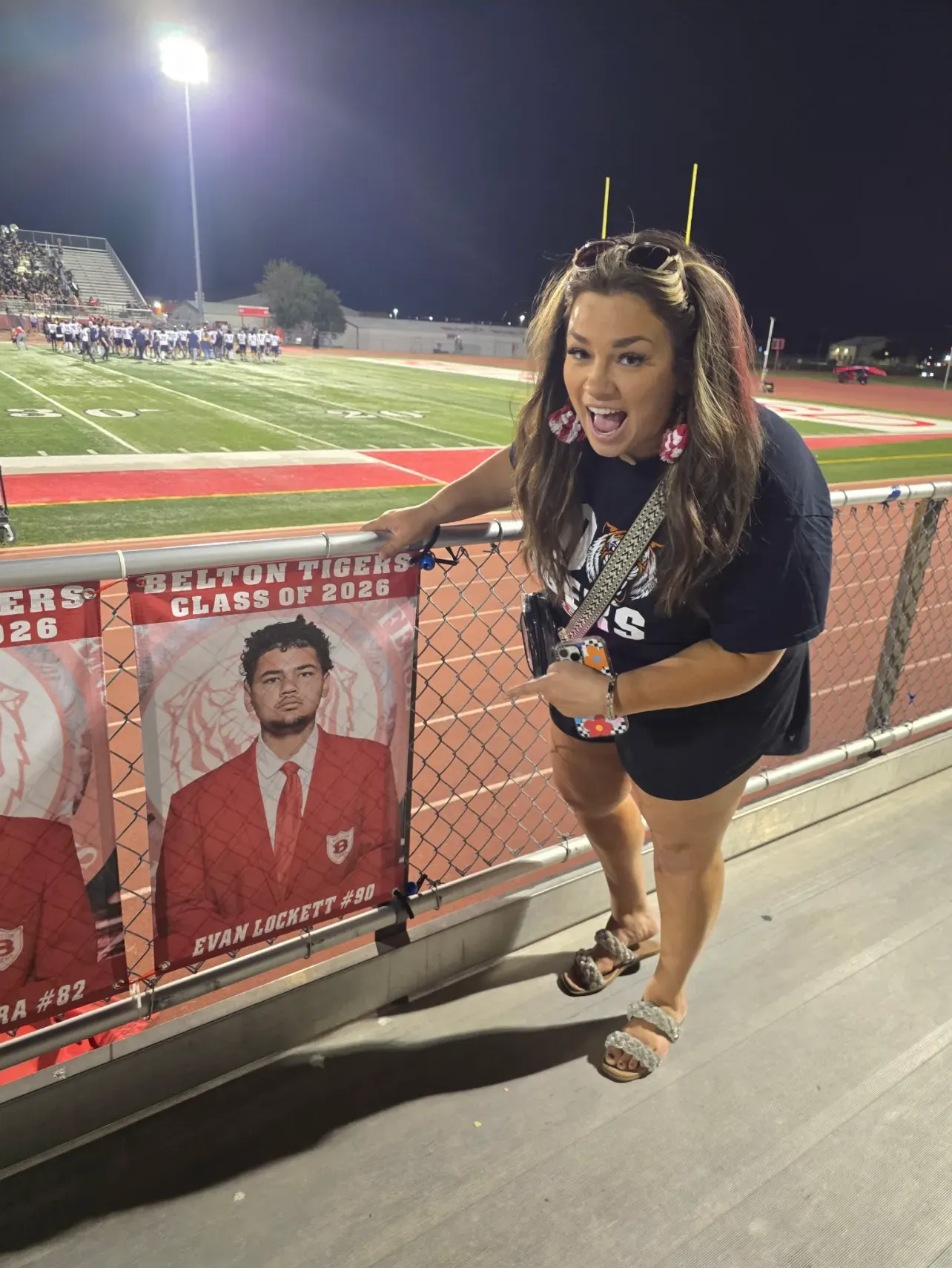 Mallory showing off family members graduation sign at football game.