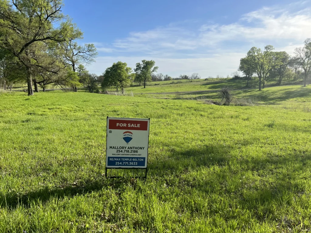 Green field with for sale sign