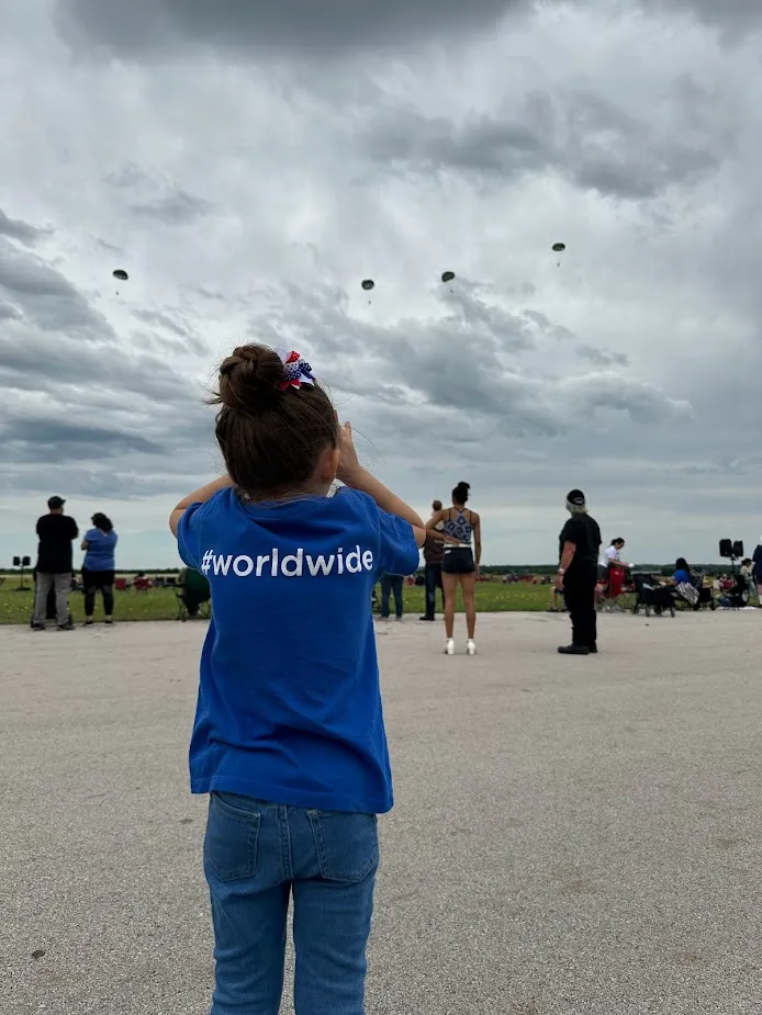 crowd looking at people coming down the sky in parachutes